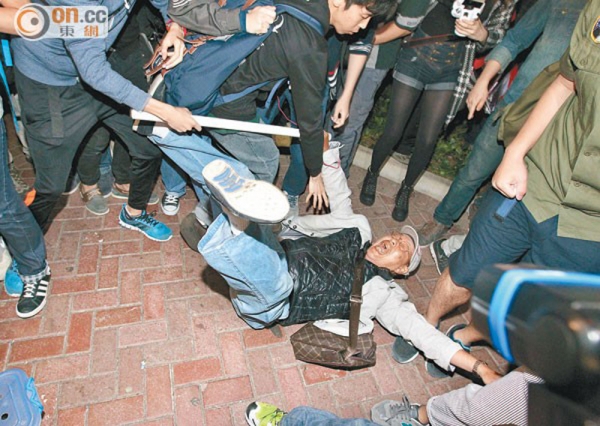 2015年3月8日，約一百五十名戴口罩的反水貨客示威者，突破警方防線，衝進屯門。示威者輪流衝擊屯門三大商場的藥房及金行，令大量店鋪關門。又在街頭指罵內地遊客、踢行李箱，連部份港人亦因被誤會是內地人而遇襲。圖為示威者將一名老人推倒。