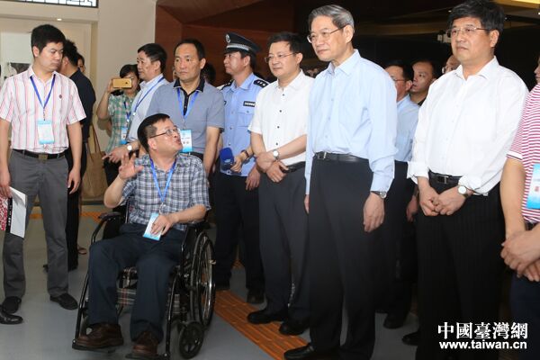 中共中央臺辦、國務院臺辦主任張志軍與福建省殘聯副理事長楊小波(坐輪椅者)親切交流。