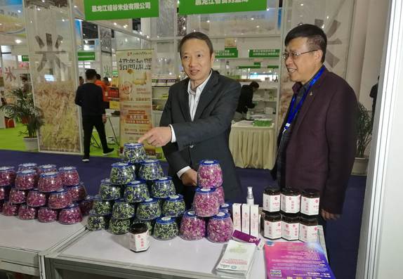 省委臺辦主任周敏謙(左)在四川雙龍農牧開發有限公司展臺與臺商林雲飛(右)親切交流